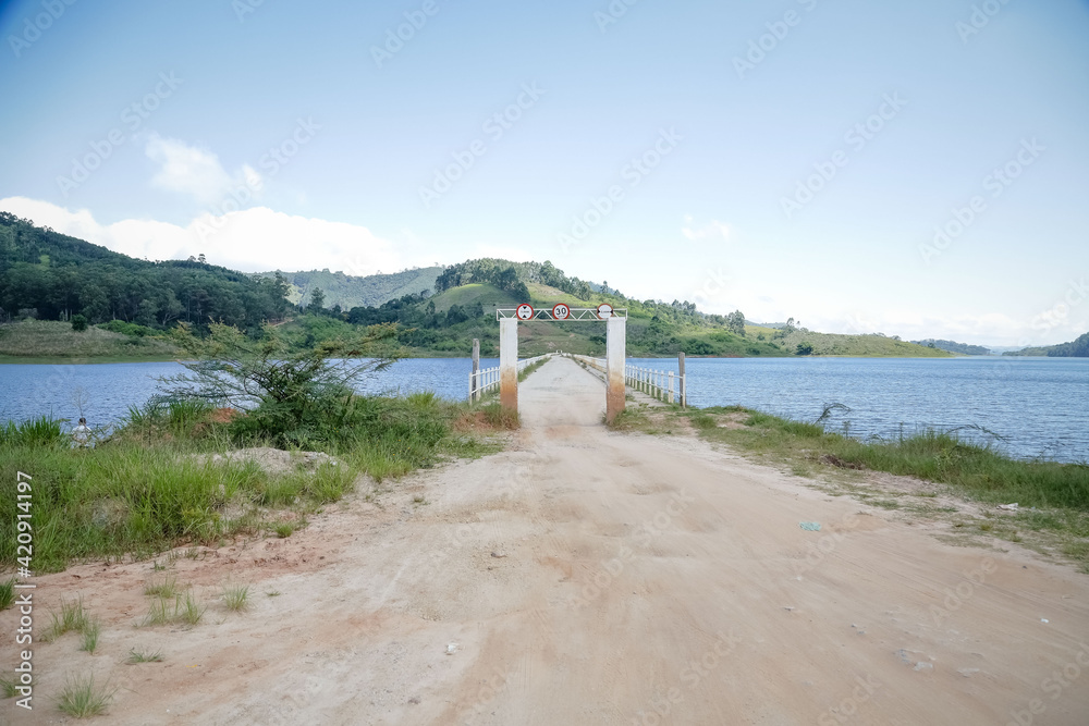 Obraz premium Um portal para entrada da represa para pescadores com lateral para aguas cristalinas e fundo da montanhas.