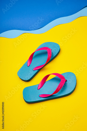 Pair of colourful flip-flops on sandy beach by sea photo