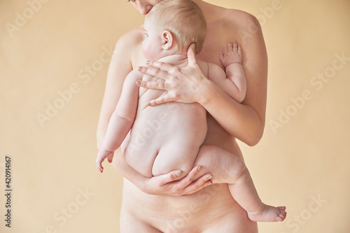 Naked mother comforting naked baby resting against her chest