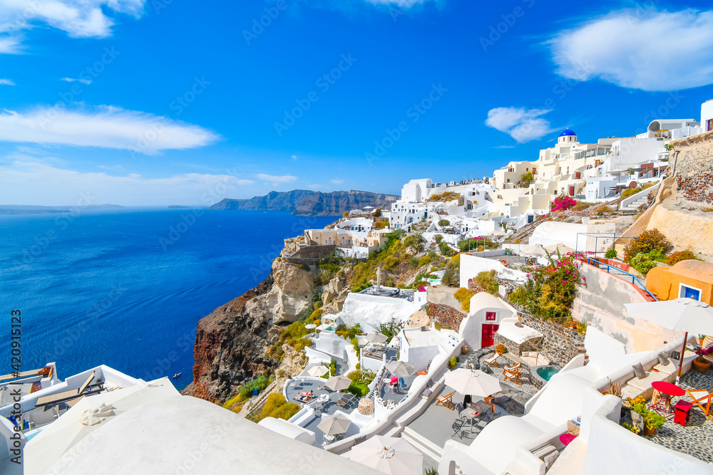 The steep cliffs of the caldera, the Aegean Sea and the whitewashed village of Oia with the Blue Dome Church in view on the island of Santorini Greece