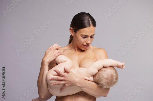Mother gently calming baby to breastfeed