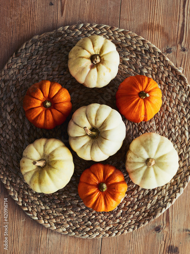 High angle close up of a selection of white and orange pumpkins on rustic place mat. photo