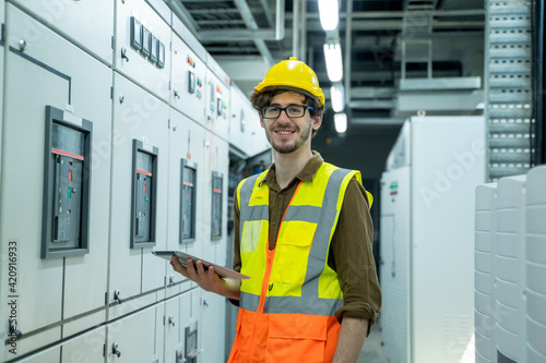 Electrician engineer using tablet computer working in control room.