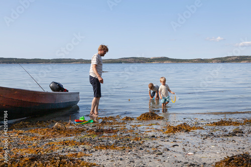 Father and sons playing beside boat moored on beach, Norway