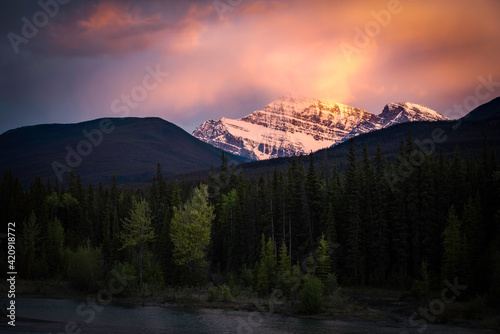 A vivid sunset along the Athabasca River as the clouds above Mount Edith Cavell catch fire in Jasper National Park.