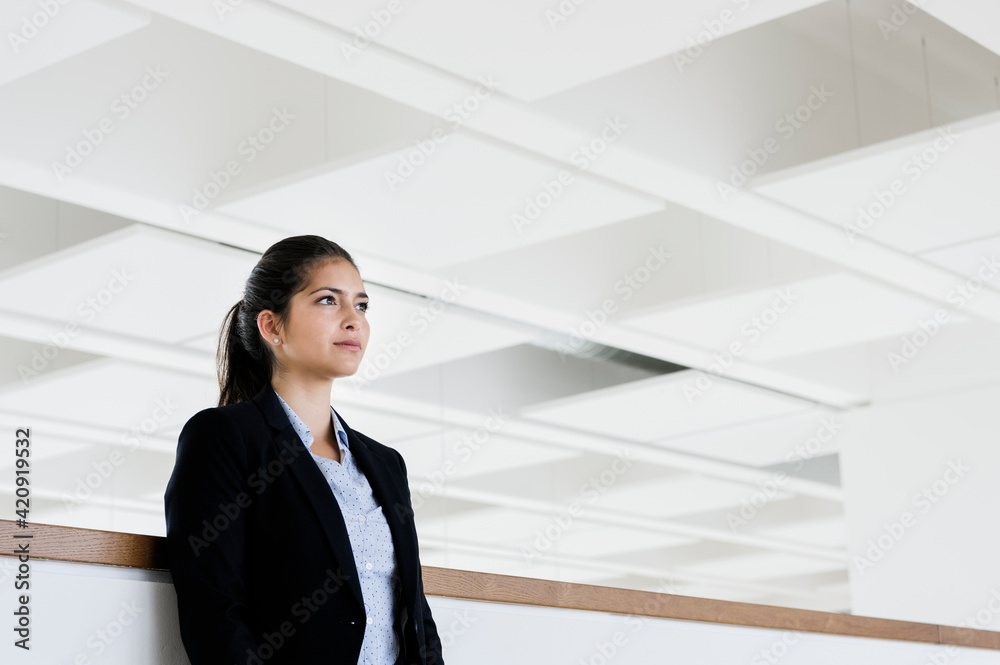 Young businesswoman taking break at corridor of office building Young businesswoman taking break at corridor of office building