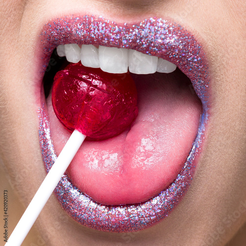 Shimmering lips biting on lollipop