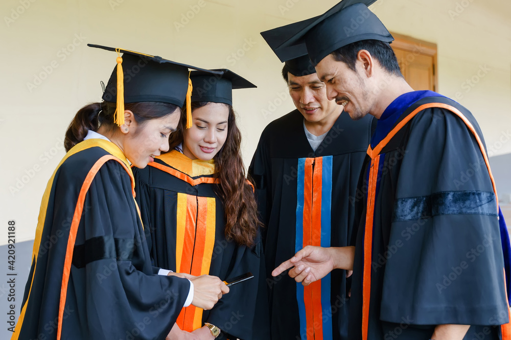 The Asian university graduates in graduation gown and a mortarboard cap with a degree certificate in hand celebrating education achievement in the commencement ceremony. Congratulations to graduations