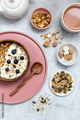 Bowl of muesli and blueberries on yogurt, assortment of seeds, brown and white sugar cubes photo