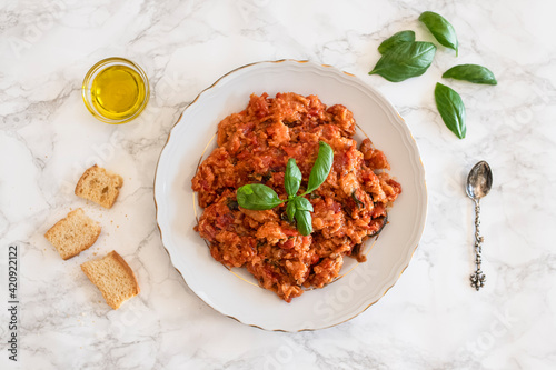 Plate of Pappa al pomodoro (Tuscan bread and tomato soup) garnished with basil, olive oil and bread on side photo