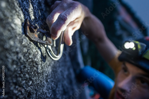 A man trad climbing at night hooking a caribiner onto a clip on Squamish, British Columbia, Canada photo