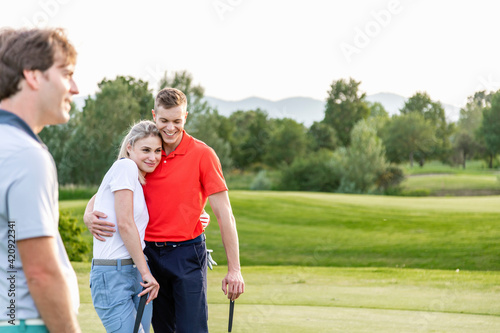 Man with couple hugging on golf course