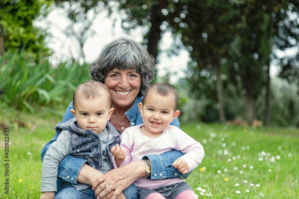 Grandmother with two grandchildren on lap in garden, Florence, Italy Grandmother with two grandchildren on lap in garden, Florence, Italy