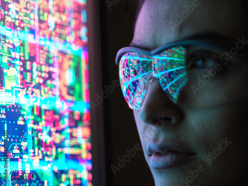 Electronic circuit board on computer monitor reflecting in glasses of a female engineer. photo