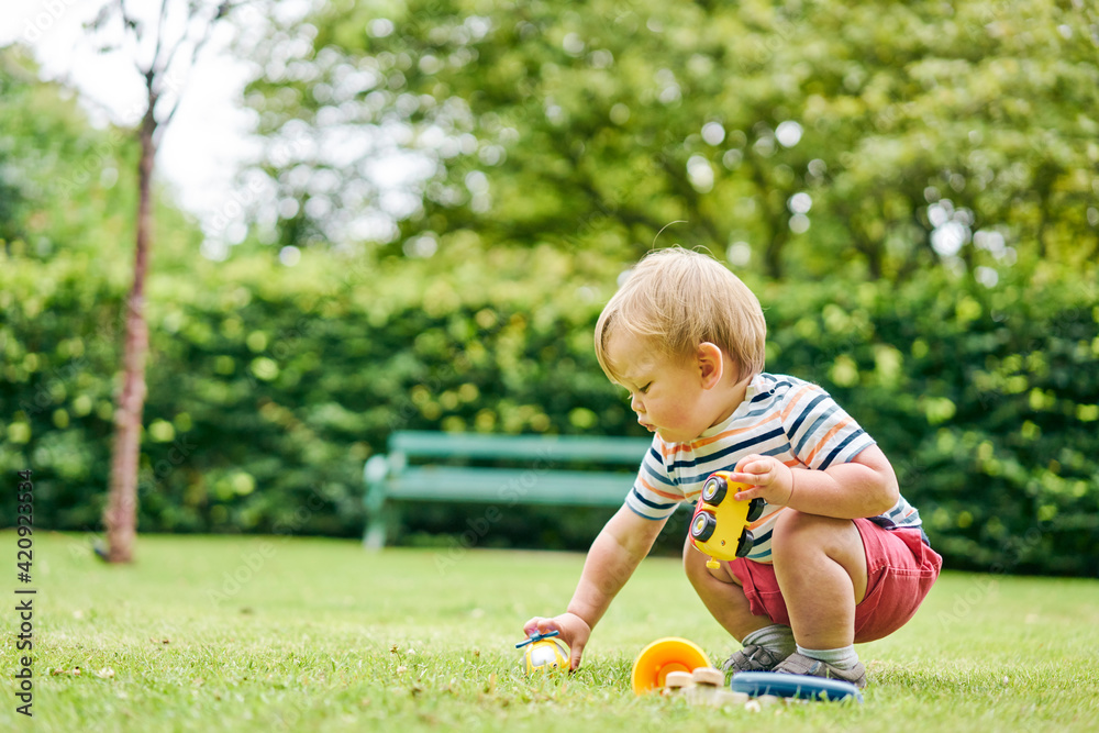 Toddler playing with toy car in park Toddler playing with toy car in park
