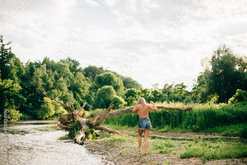 Rear view of young woman wearing shorts walking along a river bank. photo