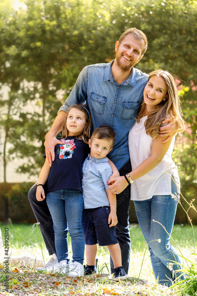 Family portrait, man and woman standing outdoors with boy and girl, smiling at camera. Family portrait, man and woman standing outdoors with boy and girl, smiling at camera.