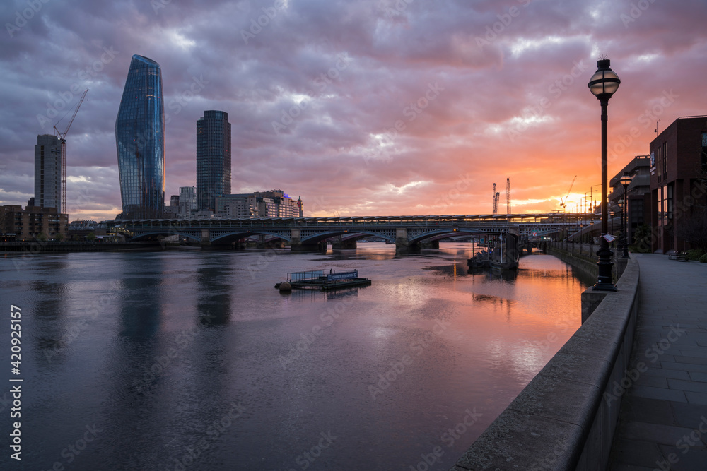 View from Blackfriars Bridge at sunset, River Thames and modern buildings, and the setting sun.  