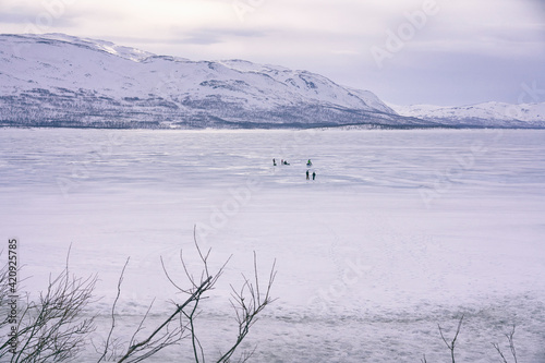 View across frozen lake with people in the distance, Vasterbottens Lan, Sweden. photo