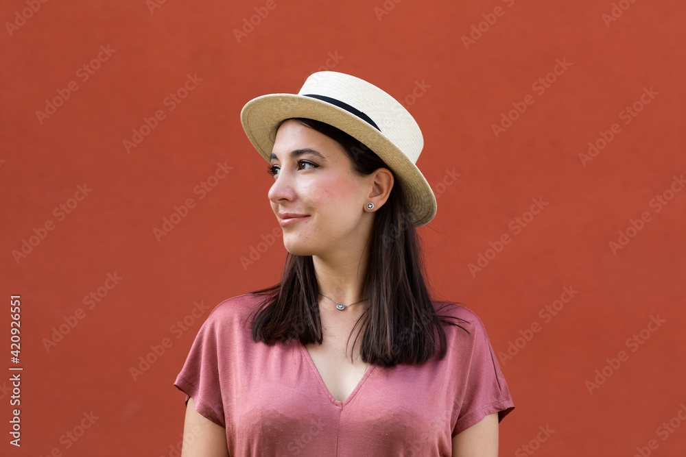 Portrait of woman wearing dusty pink top and straw boater, plain background Portrait of woman wearing dusty pink top and straw boater, plain background