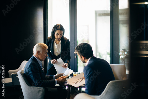 Businesswoman and men having meeting in hotel restaurant