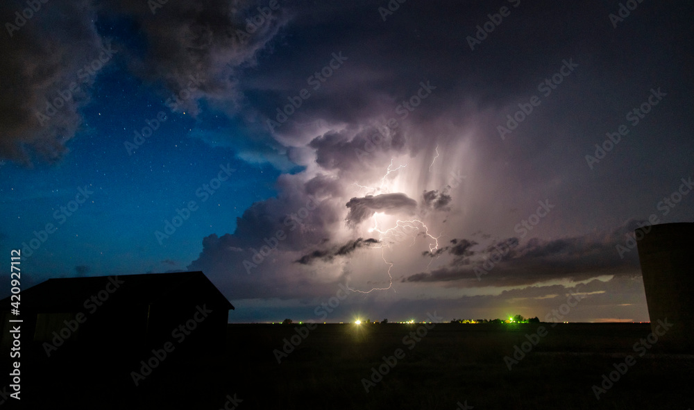 Numerous cloud-to-cloud lightning strikes seen along the dryline at night, with stars in the background over farm buildings Numerous cloud-to-cloud lightning strikes seen along the dryline at night, with stars in the background over farm buildings