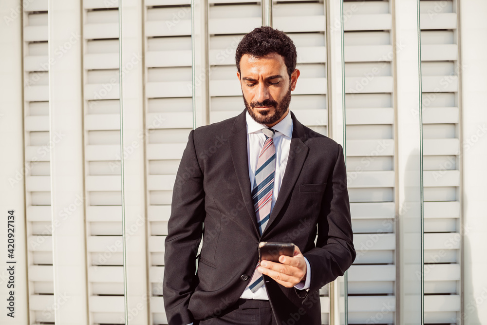 Portrait of bearded businessman wearing dark suit, checking mobile phone. Portrait of bearded businessman wearing dark suit, checking mobile phone.
