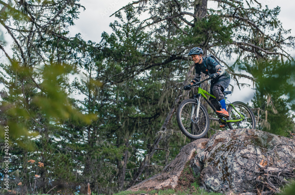 Woman mountain-biking in a forest in the Canadian mountains in British Columbia. Woman mountain-biking in a forest in the Canadian mountains in British Columbia.