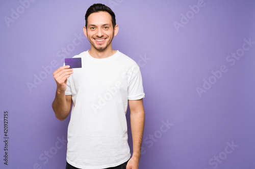 Hispanic man with a beaming smile showing his credit card