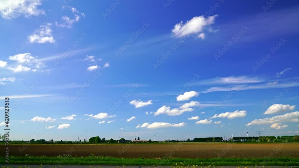 Time-lapse of uncultivated farmland in spring, white clouds floating in blue sky Time-lapse of uncultivated farmland in spring, white clouds floating in blue sky
