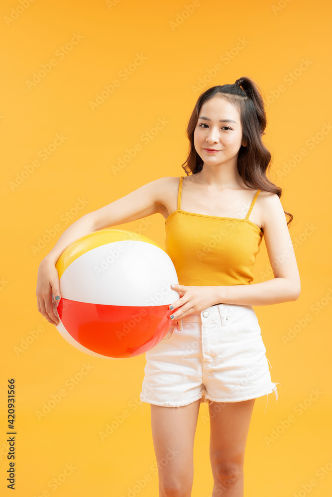 smiling teenage girl with beach ball over yellow background smiling teenage girl with beach ball over yellow background
