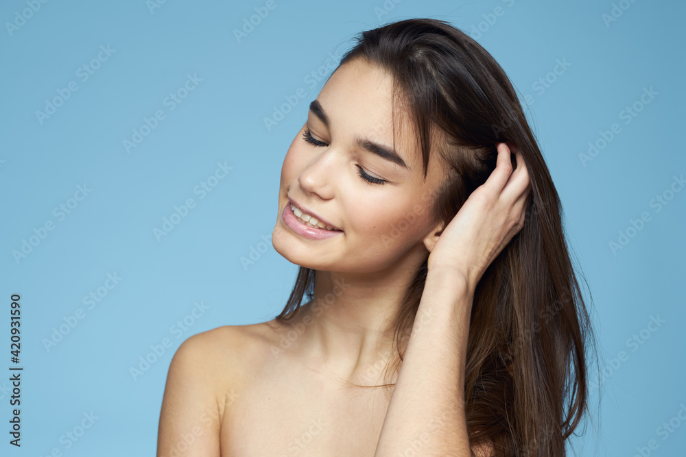 Pretty woman naked shoulders hair care close-up bank blue background Pretty woman naked shoulders hair care close-up bank blue background