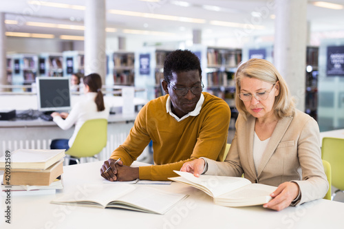 Two adult students studying together in public library. High quality photo