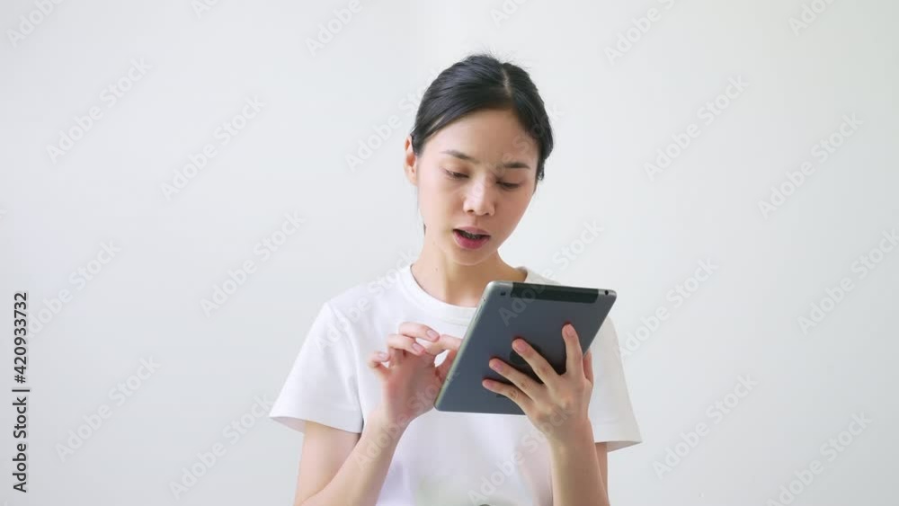 Cheerful beautiful Asian woman in a white t-shirt and look talk to camera at video calling recording with online chat at house. Cheerful beautiful Asian woman in a white t-shirt and look talk to camera at video calling recording with online chat at house.