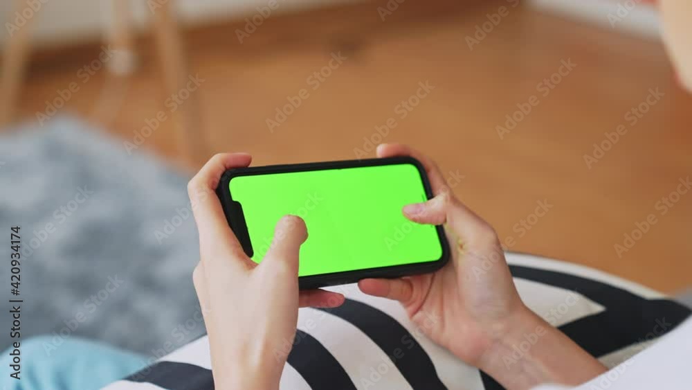 Young Asian woman holding in hands a smartphone with green screen for playing games, chromakey screen for advertising. Young Asian woman holding in hands a smartphone with green screen for playing games, chromakey screen for advertising.