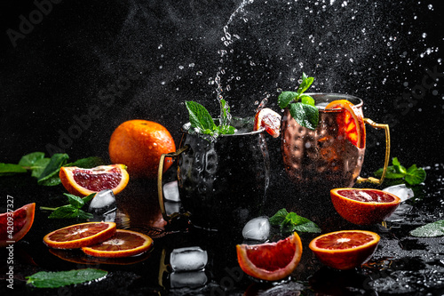 Photography blood orange Moscow mule alcohol cocktails with fresh mint leaves and ice in cop