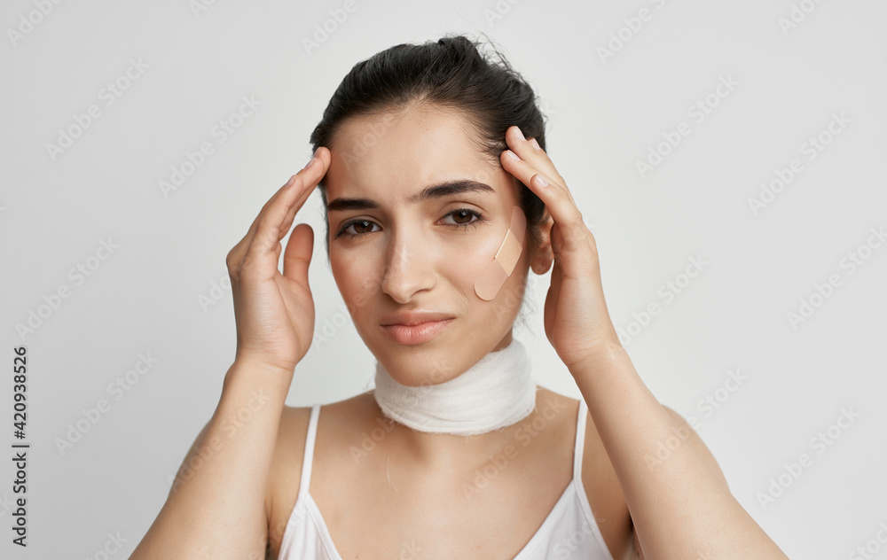 brunette with a bandaged neck holding her head health problems brunette with a bandaged neck holding her head health problems