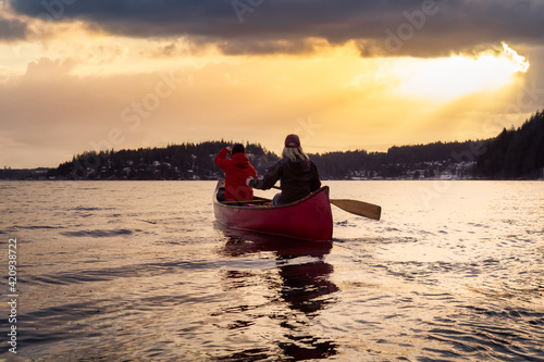 Couple friends on a wooden canoe are paddling in water. Dramatic Sunset Sky Art Render. Taken in Indian Arm, near Deep Cove, North Vancouver, British Columbia, Canada. Concept: Adventure, Explore © edb3_16