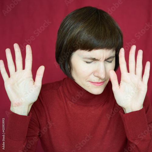 Portrait of mature woman in distress, hands up, stoping situation, stop gest. Agitated tensed face. Middle-aged beautiful female. Excess information. Difficult situation, problems. Anxiety, stress photo