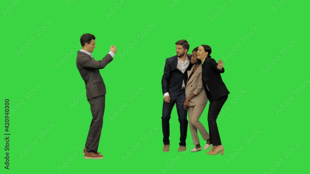 A young man in suit taking a picture of his friends, while they are dancing on a Green Screen, Chroma Key. A young man in suit taking a picture of his friends, while they are dancing on a Green Screen, Chroma Key.