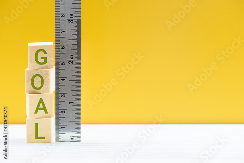 Evaluating goals and the success of business strategic process, business concept : Word GOAL on cubes, measured by a ruler, depicts setting and evaluating a company or employee goals and performance