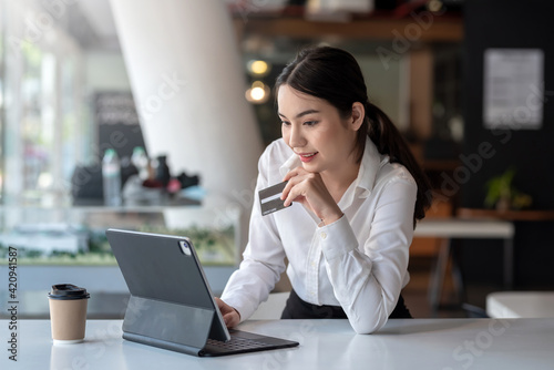 Asian woman shopping online through tablet pay by credit card at a coffee shop.