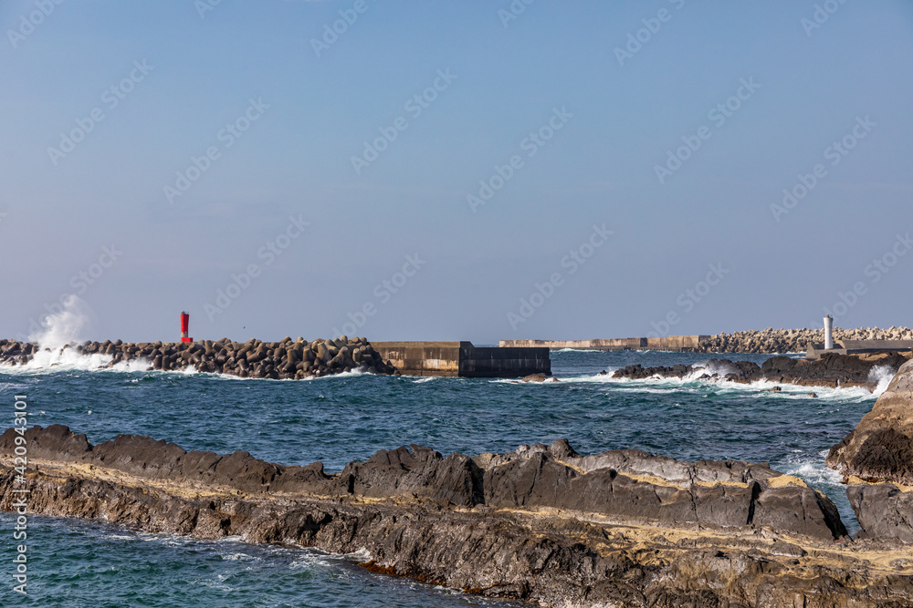 岩場にある港の防波堤の赤色灯台と白灯台