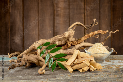 Eurycoma longifolia Jack,dried roots,green leaves and powder on an old wooden background.