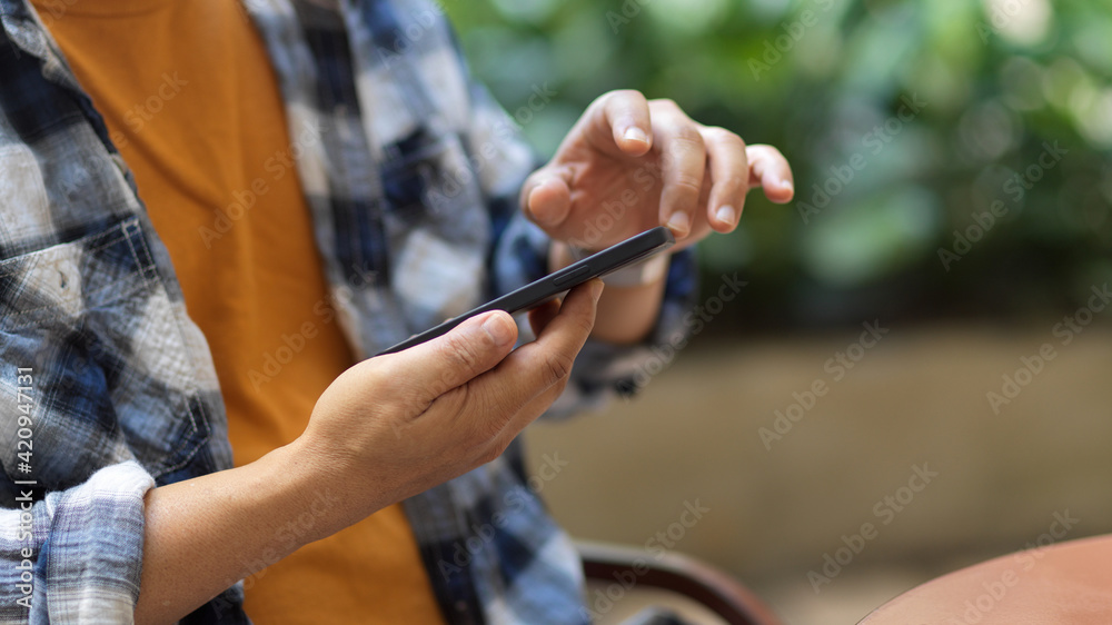 Male freelancer using smartphone in his hands while relaxing in garden at home Male freelancer using smartphone in his hands while relaxing in garden at home