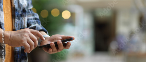 A man touching on smartphone screen while standing in blurred background