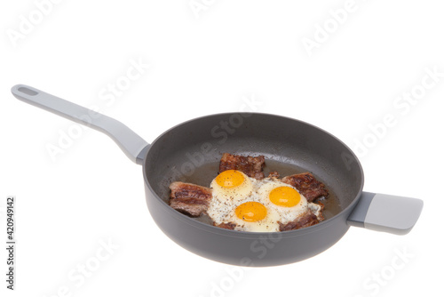 fried scrambled eggs with bacon in a frying pan