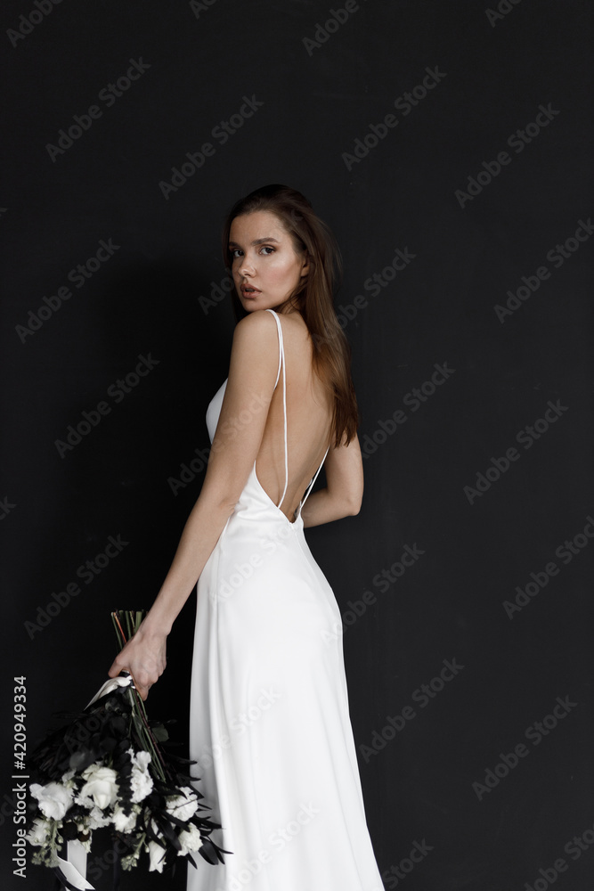 Beautiful woman in a white wedding dress on a black background. A modern trendy bride in an elegant dress. Beautiful woman in a white wedding dress on a black background. A modern trendy bride in an elegant dress.