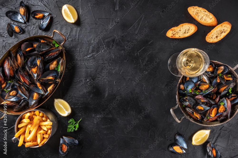 Fototapeta Mussels with wine, lemon, and French fries, overhead flat lay shot