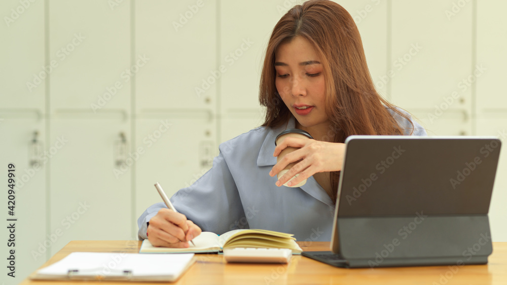 Businesswoman holding coffee cup while working with paperwork in office room Businesswoman holding coffee cup while working with paperwork in office room